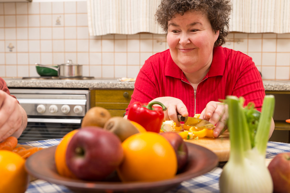 A person with disabilities chops vegetables. 